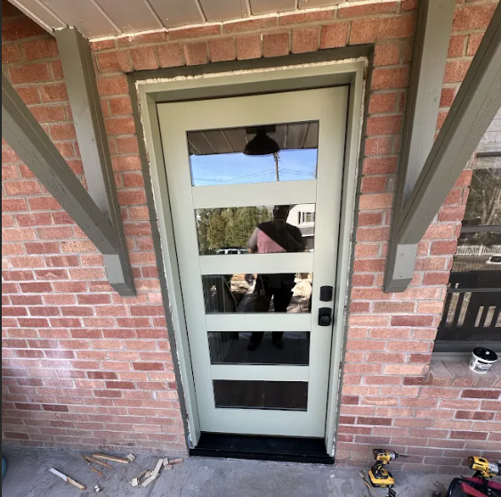 New green entry door with horizontal glass panels in a brick home